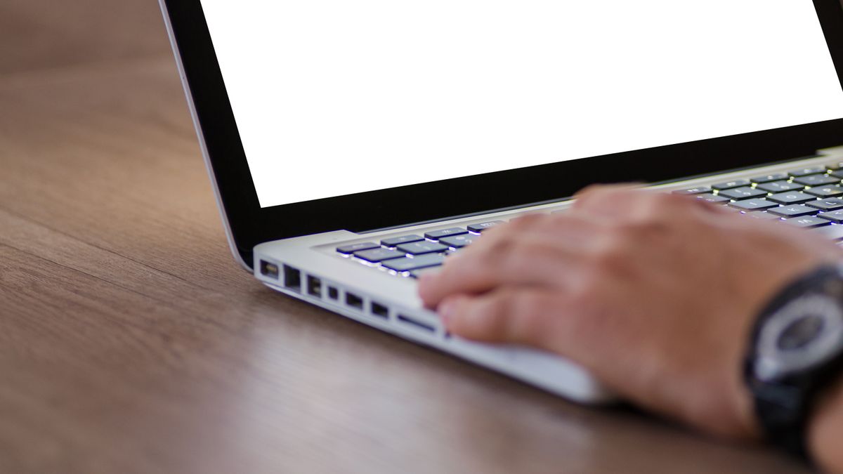 デスクでノートPCのキーボードに手を置いているイメージ