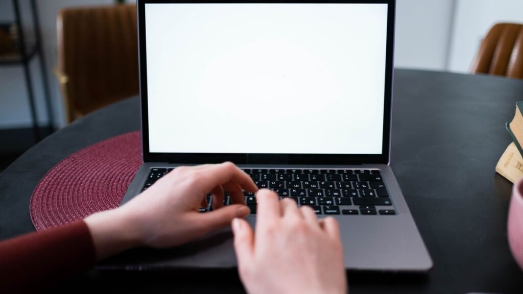 夜、ノートPCのキーボードに手を置いているイメージ