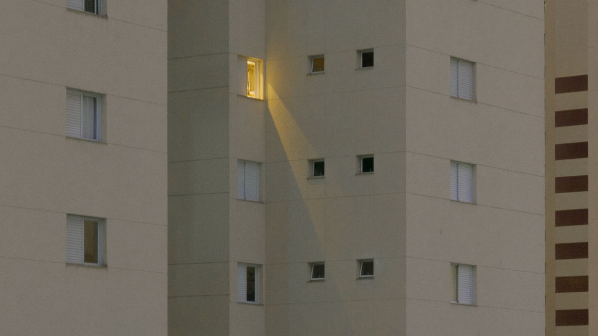 夜、明かりが灯る一室だけが目立つマンションの外観