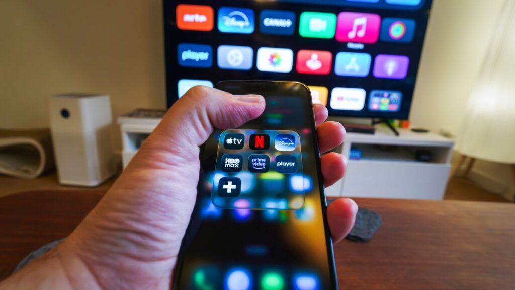 テレビの前でスマートフォンの配信アプリ一覧を持っている手元のイメージ