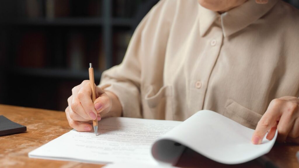 机の上で書類を一枚ずつ確認する手元