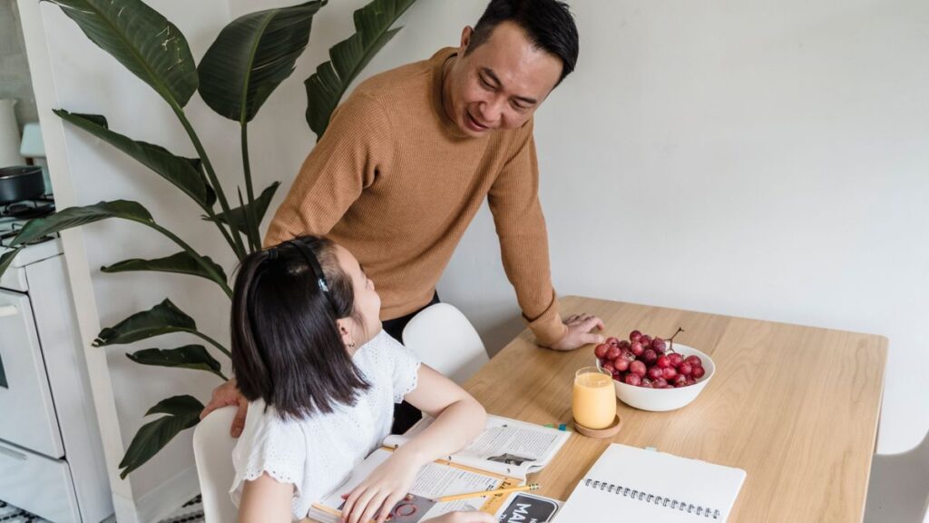 ダイニングテーブルで子どもの宿題を見る保護者