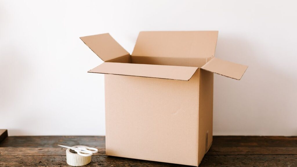 発送の準備をする机の上に置かれた段ボール箱とテープとはさみ
