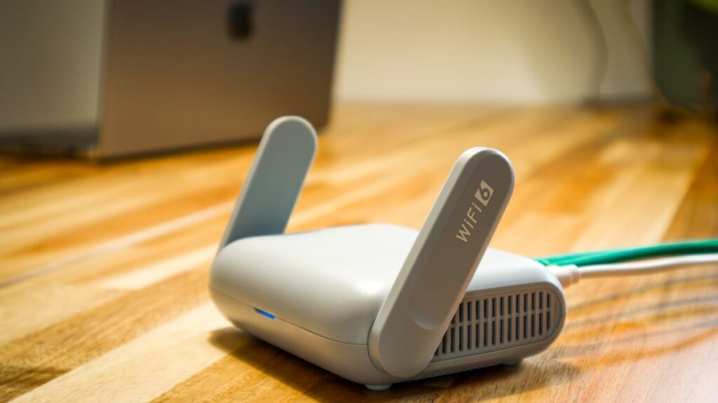 木の机に置かれたアンテナつきの無線ルーターとケーブル