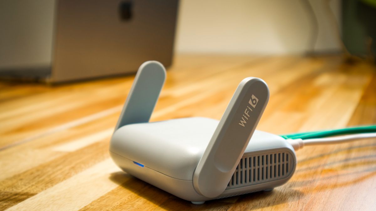 木の机に置かれたアンテナつきの無線ルーターとケーブル