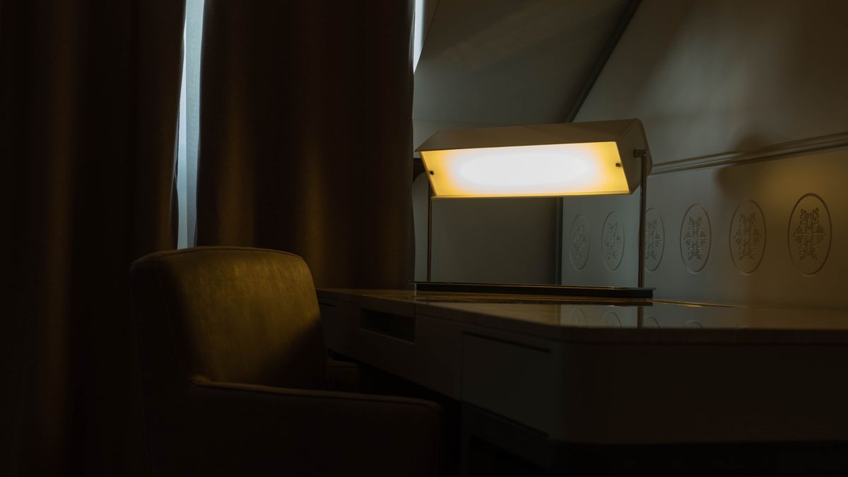 スタンドライトで全体が暖かく照らされた、机と椅子だけの部屋の一角