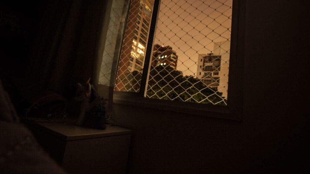 夜の室内から窓越しに街の明かりが見えている様子