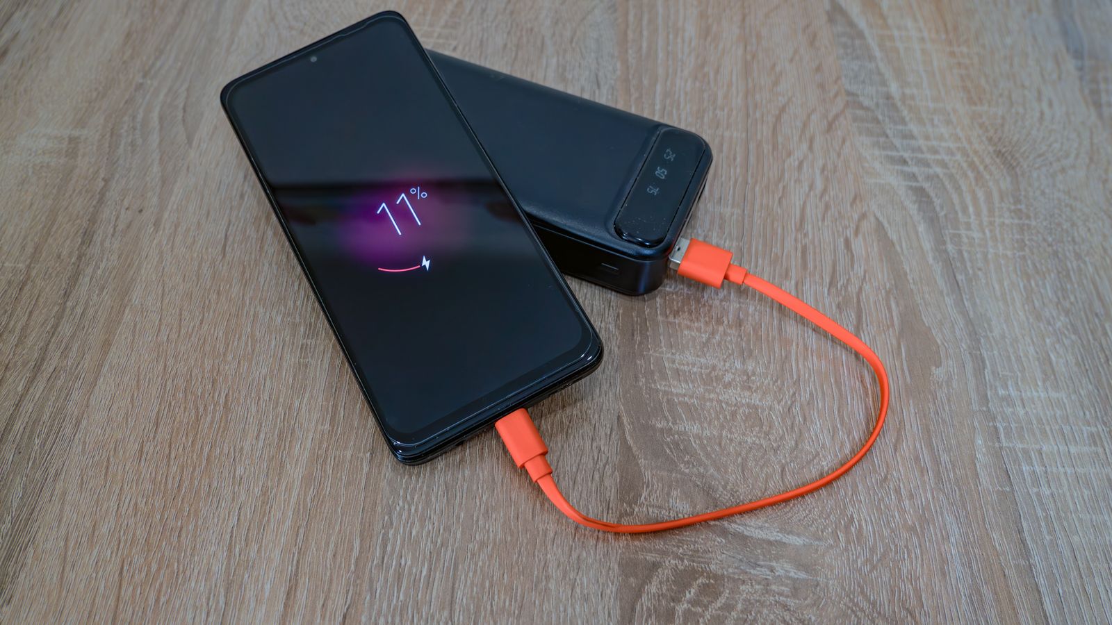 スマートフォンがモバイルバッテリーにケーブルで接続され充電されている様子