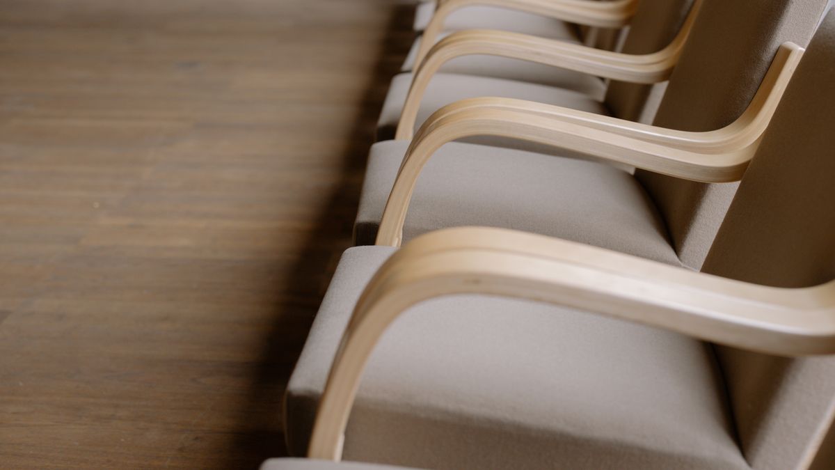 木のひじ掛けの椅子が一列に並んだ空の会議室。Notionのゲストとメンバーの分け方を解説する記事のアイキャッチ