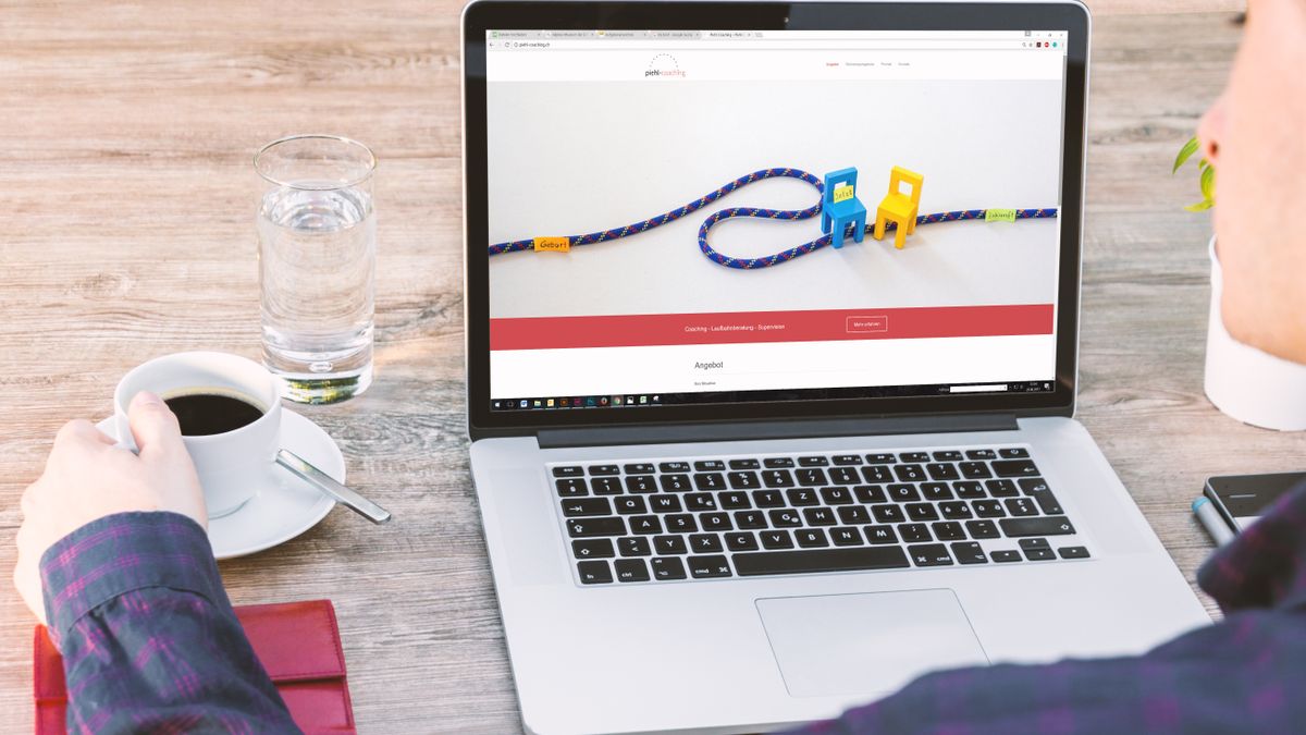 ブラウザでWebサイトを開いているノートパソコンとコーヒーカップ