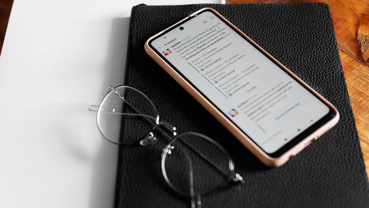 チャットアプリを開いたスマートフォンとメガネが置かれたデスク