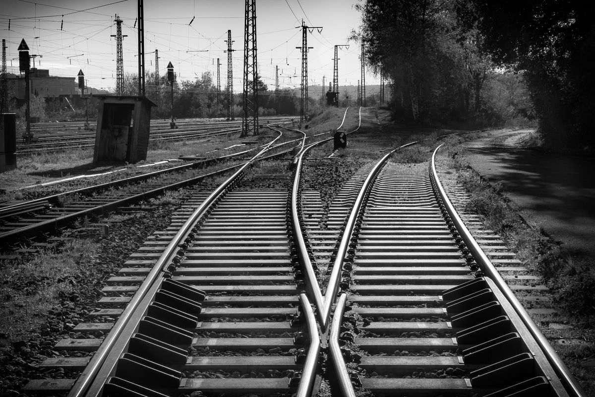 白黒写真。2本の線路が手前で交わっている