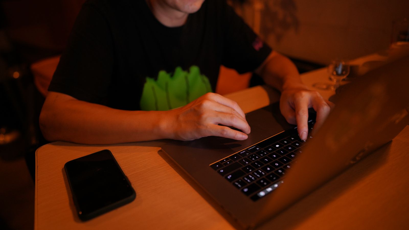 夜の自宅でノートパソコンに向かって作業をしている人の手元のイメージ